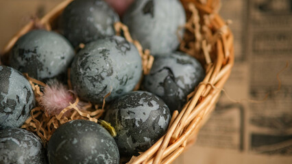 Easter card with a copy of the place for the text. Purple, blue eggs in a basket on a dark newspaper background. Natural dye karkade tea.