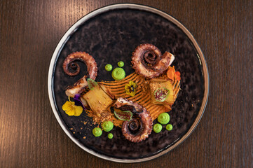 Octopus with potatoes on pea mash decorated with edible flowers