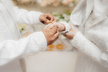 A man puts a bracelet on his partner's hand during a wedding in Lhokseumawe City, Aceh. Pernikahan...