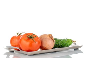 Two ripe tomatoes, cucumber and onion on a metal tray, macro, isolated on a white background.