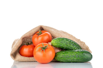 Three ripe tomatoes and two cucumbers with a jute bag, macro, isolated on a white background.