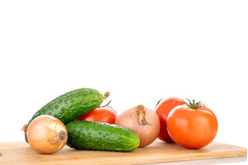 Three ripe tomatoes, two onions and two cucumbers on a wooden cutting board, macro, isolated on a white background.