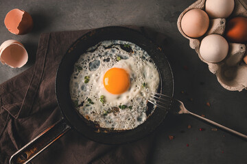 Fried egg in a cast-iron pan, rustic style, selective focus, horizontal, no people, top view.