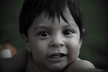 Very young Latino baby looking directly at the camera with an expression