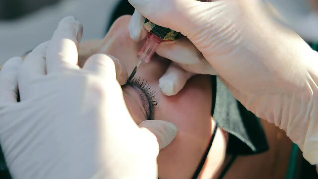 Master of permanent make-up creates eyebrows for a woman's client. Eyebrow tattoo close up. Marking and creating eyebrows with permanent makeup