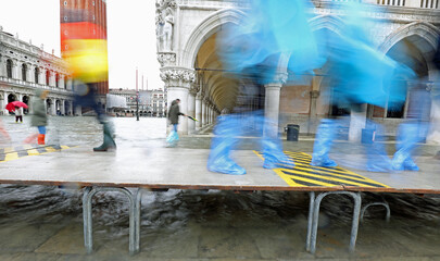 People moving fast on the elevated walkway in Venice at high tide