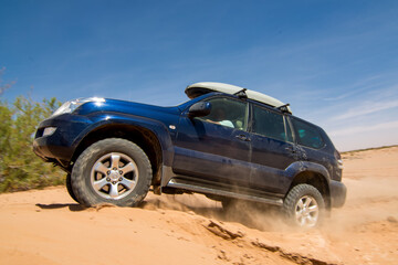 Fototapeta na wymiar 4x4 driving up a sand dune on a sunny day