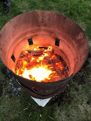 Fast abgebranntes Osterfeuer . Glühende Glut in einem Metallfass . Lagerfeuer oder Campfire in der Tonne aus Metall . Ghetto Straßenfeuer in Metalltonne concept foto . Fossiler Energieträger für Wärme