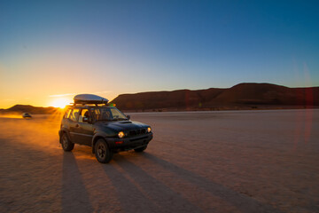 An all-terrain vehicle driving fast through the desert at sunset