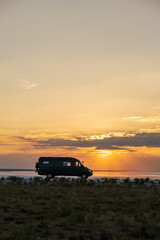 Fototapeta na wymiar Backlighting silhouette of a camper next to a salt lake at sunset
