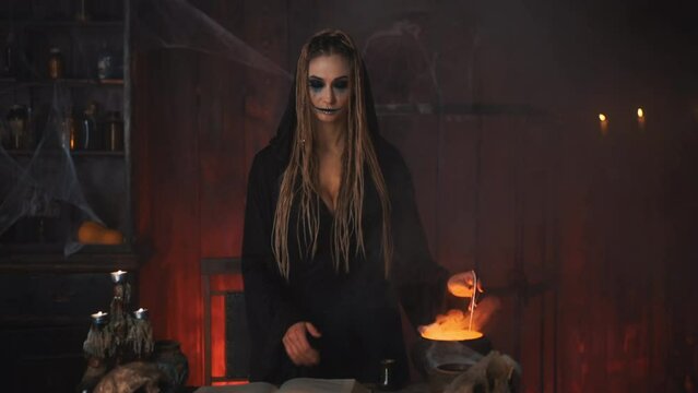 Come here. Halloween concept. Halloween, witch use magic book and cauldron prepare poison or love potion standing dark room invite with hand gesture. Jack lantern head. Female necromancer Handheld 