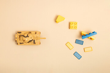 Tank, dominos and toy blocks on sand color background. Minimal Ukraina concept. Top view. Flat lay.