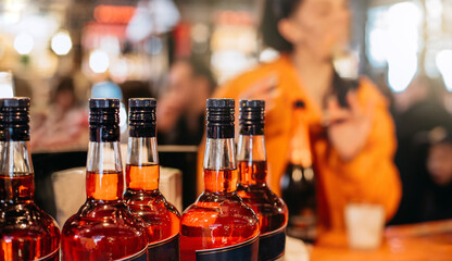 bottles of aperitif in the foreground of a bar with a blurred orange background and unrecognizable people. concept liquors and aperitif.