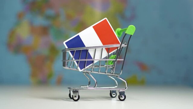 France national flag in miniature shopping trolley cart. Export shopping online or ecommerce delivery service, shipping, duty, trade concept. World map on the background.