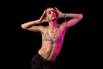Young model with tattoos, shirtless and makeup. Posing with a black background and magenta light. Showing her feelings.