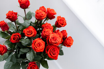 Beautiful bouquet of red roses wedding flowers on white background. Light minimal interior, decoration of apartment, copy space