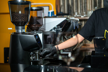 Close-up image of the coffee grinder machines in a coffee shop. Barista grinding freshly roasted coffee beans from a professional modern electric grinder into a powder. Cafe brewing Service Concept