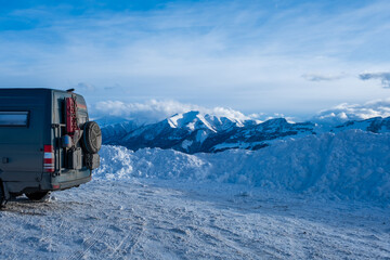 Dirty 4x4 camper van in snowy landscape with incredible clouds behind