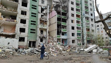 Rear view of a man standing outside a destroyed building following an air strike by the Russian army on Ukraine. A destroyed building after a rocket attack in ukrainian city Chernihiv.