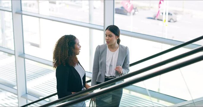 The beginning of the day. 4k video footage of two attractive young businesswomen going up the escalator at work.
