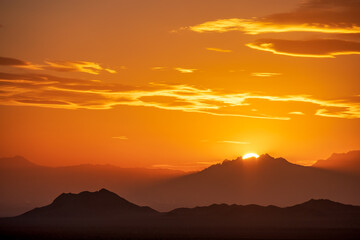 Rugged reliefs of the mountains in the Iranian desert with the sun setting behind them