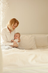 mother with a child at white bedroom, small baby boy with mom. mathernity and childhood