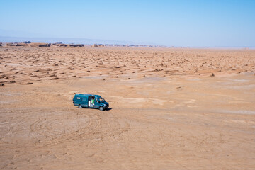 Obraz premium Woman in the middle of the desert in her campervan with a green shirt