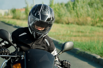 Woman biker in black motorcycle safety helmet driving a motorcycle. Active hobby, travel.