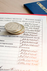Russian certificate with good grades in all subjects and metal Russian coins.. The concept of the economic crisis in Russia. Vertical photography.