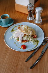 Pancakes with caesar salad between them. Breakfast in an inexpensive cafe. Coffee