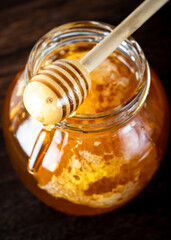 Honey dipper pouring honey in the jar. Wooden honey dipper taking honey from the jar. 
