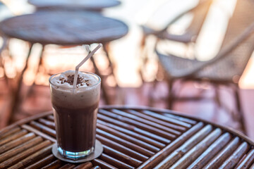 Iced chocolate topped with cocoa flavor and whipped cream in a tall glass served in a coffee shop...