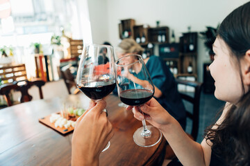 clinking wine glasses - women taking photos with mobile phone