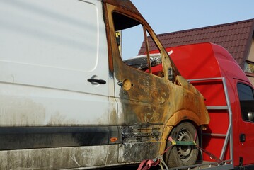 part of one big white minibus car with brown charred cab on the street
