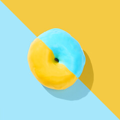 blue and yellow donut with glaze on blue and yellow pastel background