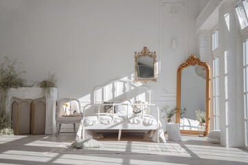 Morning in light bedroom with mirror in golden frame in style of rococo.
