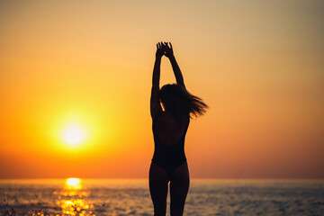 Silhouettes of a girl against the background of the sea and the setting sun