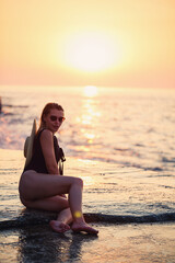 Fototapeta na wymiar Beautiful lady in a black swimsuit on the seashore, Smiling face. Golden sunset light