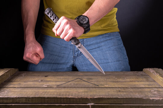 Combat knife grip. Knife fight. Stab. The man is holding a large narrow knife.