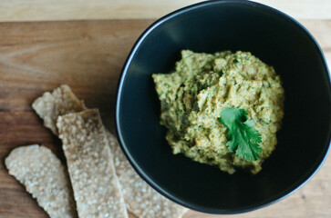 Guacamole in a black bowl with crackers