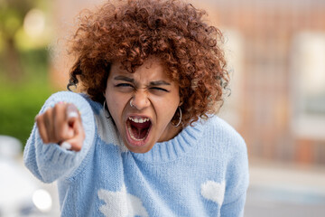 portrait of angry or furious girl accusing and pointing finger - obrazy, fototapety, plakaty