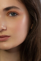 Obraz premium Close up beauty of a half face of a woman with wet radiant skin and big gray eyes. Fashionable natural makeup and wet facial hair. Pink lipstick with kissed lips