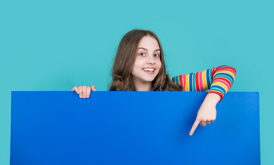 smiling child behind blank blue paper with copy space for advertisement