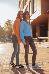 Full shot portrait in low camera angle of female twins in the same clothes.