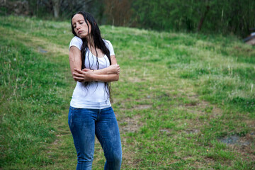 photo of long-haired brunette girl hugging herself in the rain on a sad day after receiving bad news. loss, loneliness and sadness. anxiety and depression. mental health. mental illness - copy space