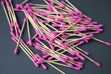Pink cotton swabs lie in a heap on a gray background top view the concept of hygiene and self-care