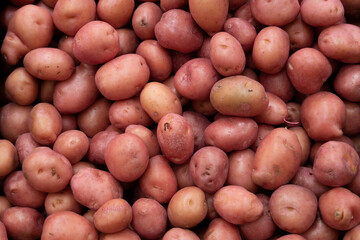 A scattering of red potatoes at a vegetable market. A pile of fresh potatoes in a supermarket. Potato background.