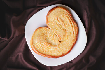 delicious ear-shaped puff pastry bread with sugar on a white ceramic homemade plate
