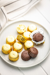 Wrapped chocolate pralines. Sweet chocolate bonbons on plate.
