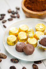 Wrapped chocolate pralines. Sweet chocolate bonbons and cocoa beans.